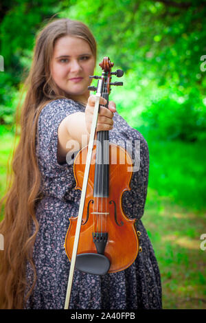 Das Konzept der Musikinstrumente. Schöne Mädchen hält eine Violine in den Händen. Frau Musiker mit einem musikalischen Thema aufwirft. Stockfoto