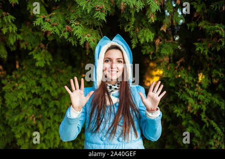 Junge schöne Mädchen in einer blauen Jacke. auf einem grünen Hintergrund. Ein Portrait von ihr, sie ist schön, attraktiv, süß, süß, attraktive, junge Mädchen in Stockfoto