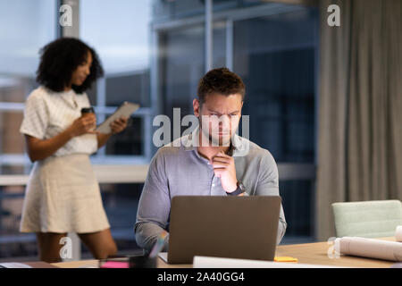 Zwei junge kreative Fachleute, die spät in einem modernen Büro Stockfoto