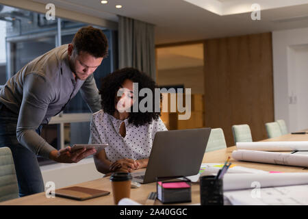 Zwei junge kreative Fachleute, die spät in einem modernen Büro Stockfoto