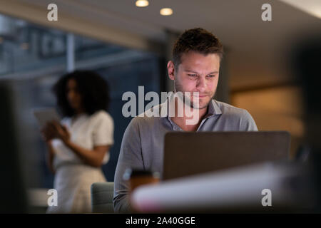 Zwei junge kreative Fachleute, die spät in einem modernen Büro Stockfoto