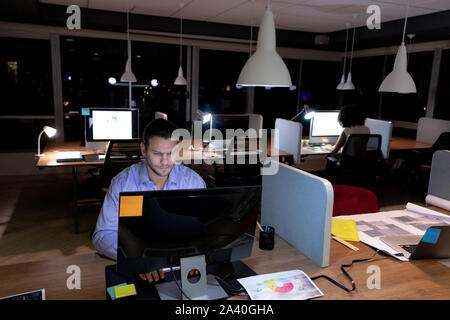 Zwei junge kreative Fachleute, die spät in einem modernen Büro Stockfoto