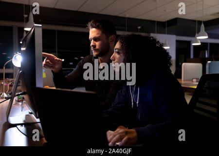 Zwei junge kreative Fachleute, die spät in einem modernen Büro Stockfoto