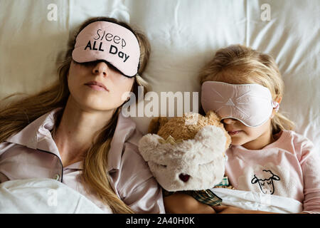 Hohes Ansehen der kaukasischen Mutter und Tochter, gefüllte Teddybär Spielzeug schlafen in Augenbinden auf dem Bett im Schlafzimmer zu Hause. Entspannen, Familie, Liebe Stockfoto