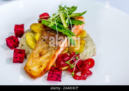 Knusprige gehäutet Atlantischen Lachs mit gebratenen Kartoffeln, sautierten Spargel und Baba ghanoush, mit Sojasprossen und Drachenfrucht eingerichtet. Ansicht von oben Stockfoto