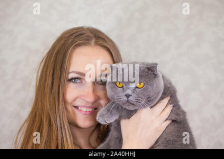 Porträt von einem schönen Mädchen mit Katze. Hält eine Frau eine Katze in die Arme. Süße flauschige Haustiere und ihre Besitzer. Stockfoto