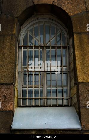 Düstere Fenster mit Gitter am grauen Stein Wand historischer Gebäude. Reisen Russland, Sankt Petersburg. Stockfoto