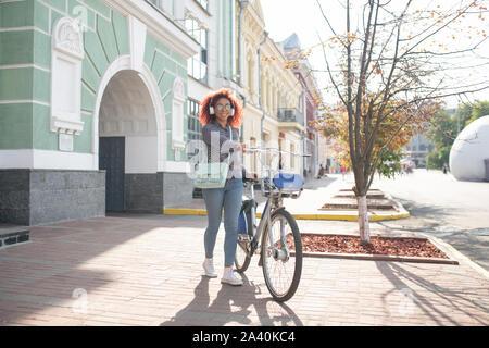 Curly student reiten ihr Fahrrad in den Morgen Stockfoto