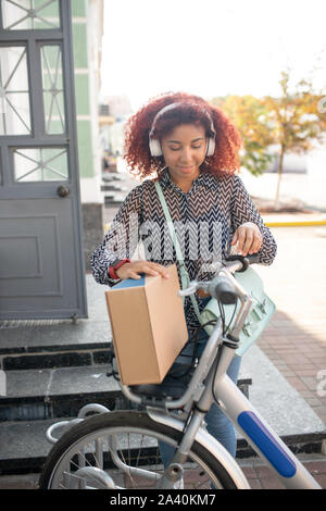 Curly student verlassen Post mit ihr Paket Stockfoto