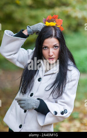 Mädchen in den Wald. Porträt eines schönen, verträumten und fröhliches Mädchen mit langen gewelltes Haar in einem weißen Herbst Mantel. Stockfoto