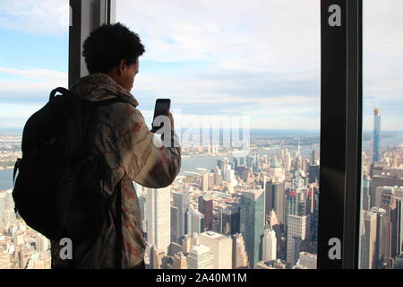 New York, USA. 10 Okt, 2019. Ein Besucher von der 102 Etage des Empire State Building fotografiert. Es ist eine der ältesten, grössten und beliebtesten Wolkenkratzer in New York - aber die Konkurrenz wächst. Mit einer teuren Sanierung der Ausstellung und Aussichtsplattformen, das Gebäude ist jetzt zurück schlagen im Wettbewerb für die Besucher. Credit: Christina Horsten/dpa/Alamy leben Nachrichten Stockfoto