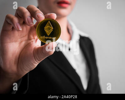 Geschäftsfrau, Gold des Astraleums Münze auf die weiße Wand im Hintergrund. Investoren Frau mit Gold des Astraleums Münze aus im Internet gefördert. Stockfoto