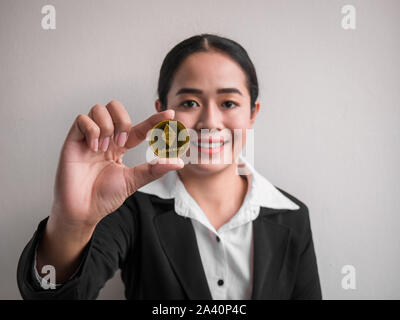 Business Frau, Gold des Astraleums Münze auf die weiße Wand im Hintergrund. Investoren Frau mit Gold des Astraleums Münze aus im Internet gefördert. Stockfoto