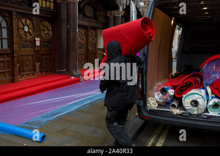 Handwerker bereiten ein Regen - getränkte roten Teppich warten auf Massen sehen öffnung Nacht der English National Opera von Orpheus und Eurydike im Kolosseum auf St. Martin's Lane, am 1. Oktober 2019, in London, England. Stockfoto