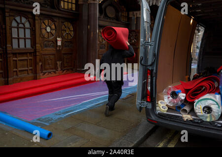 Handwerker bereiten ein Regen - getränkte roten Teppich warten auf Massen sehen öffnung Nacht der English National Opera von Orpheus und Eurydike im Kolosseum auf St. Martin's Lane, am 1. Oktober 2019, in London, England. Stockfoto