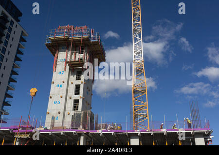 Bauarbeiter unter einem Kran ein, und heben Sie die Welle, Umfrage ein neuer Gebäudekomplex, am 2. Oktober 2019, in Sutton, London, England. Stockfoto