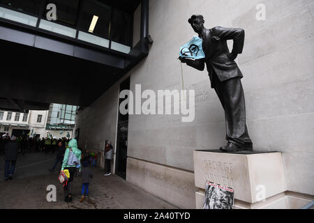 Eine Fahne auf der Statue von George Orwell außerhalb der BBC neuen Broadcasting House in London, während ein Aussterben Rebellion (XR) protestieren. Stockfoto