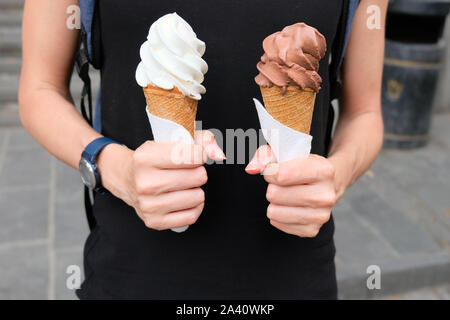 Ein Mädchen hält zwei Eistüten Schokolade und Weiß. Köstliches Eis ist das beste Dessert, im Sommer. Stockfoto