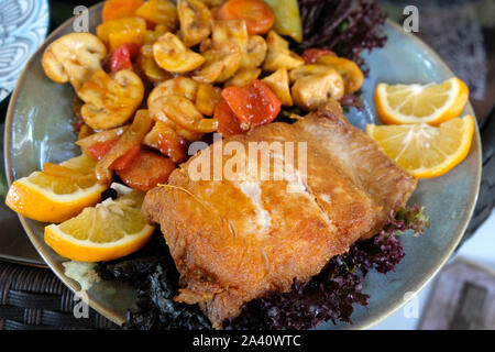 Ein Stück gebackene Forelle mit Pilzen und Gemüse auf einem Teller mit Zitronenscheiben. Köstliche georgische Küche ist ein Gericht mit Fisch, Pilze und vegetab Stockfoto
