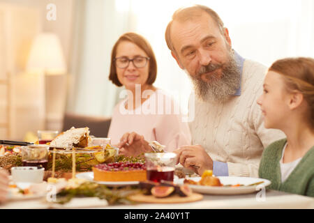 Älterer Mann mit Bart sitzt zusammen mit kleinen Mädchen am Tisch Sie die Mahlzeit und die Zeit zusammen genießen. Stockfoto