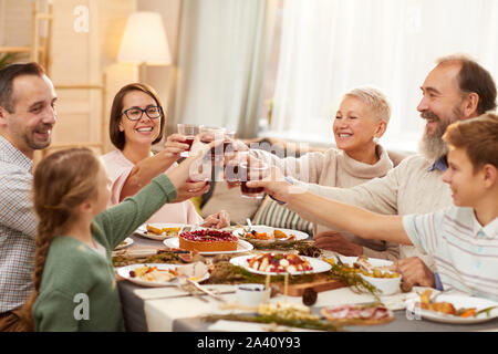 Gerne große Familie am Esstisch und Toasten mit Rotwein zusammen, während Urlaub zu Hause feiern Sitzen Stockfoto