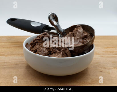 Schokolade Eis zum Nachtisch, Löffel für Eis in ein weißes Glas, Holztisch, weißer Hintergrund Stockfoto