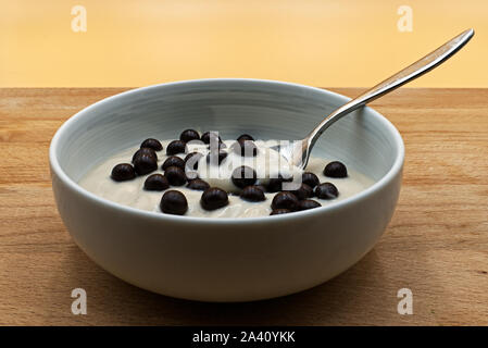 Haselnuss Joghurt mit Schokolade crispies in einem weißen Schale auf Holztisch. Stockfoto