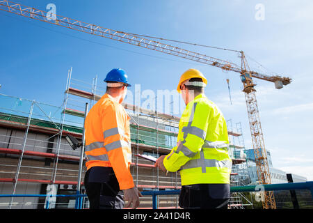 Ansicht der Rückseite zwei männlichen Architekten tragen, hardhat an der Baustelle auf der Suche Stockfoto