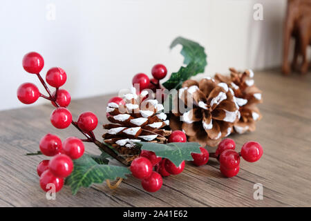 Kegel und künstlichen Zweig mit roten Beeren. Dinge, die die Einrichtung in das Neue Jahr und Weihnachten zu dekorieren. Stockfoto