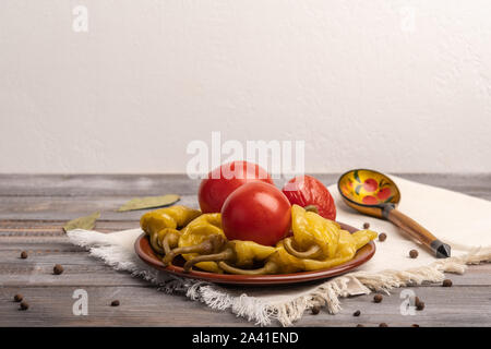 Hausgemachte eingelegte Paprika und Tomaten auf einer Keramikplatte auf einer Leinwand Serviette. Neben dem traditionellen russischen Löffel aus Holz Stockfoto