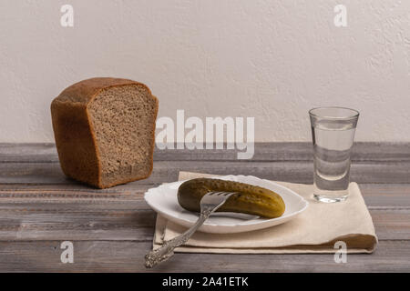 Traditionelle russische Snack - ein Glas Wodka mit essiggurken mit Gabel und Roggen Schwarzbrot. Im rustikalen Stil Stockfoto