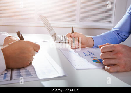 Zwei Geschäftsleute sitzen von Angesicht zu Angesicht Analyse der Business Graph im Büro Stockfoto