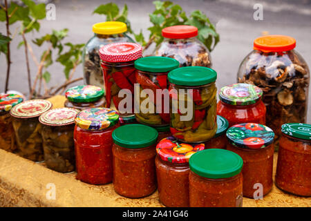 Konserven Gemüse in Gläsern. Gläser von eingelegtem Gemüse und Obst im Garten. Gebeizt essen. Eingemachtes Gemüse in Gläsern. Die Vorbereitungen für den Winter. Stockfoto