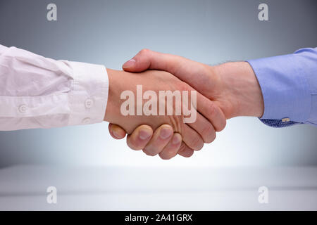 In der Nähe von zwei männlichen Geschäftsmann Händeschütteln mit Einander gegen grauer Hintergrund Stockfoto