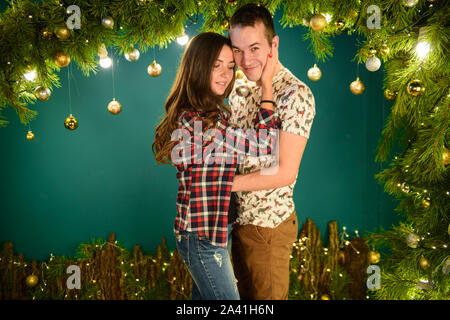 Verliebtes Paar in der Nähe von Weihnachten Hintergrund. Junges Paar Küssen in der Nähe der Weihnachtsbaum. Low Key. Silhouette Stockfoto