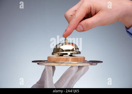 Nahaufnahme von einer Person Hand Ringing Service Bell Halten von Butler Stockfoto