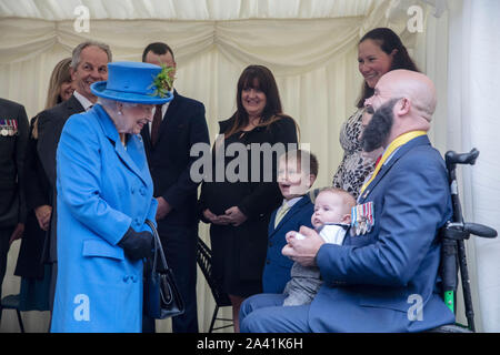 Königin Elizabeth II. Trifft sich mit Veteran Dan Phillips und sein Sohn Harry (trägt blaue und gelbe Krawatte) als sie Besuche Haig Gehäuse Vertrauen, Morden, South London, die Entwicklung des neuen Gehäuses offiziell um die Streitkräfte Veteranen und die Ex-service Community öffnen. Stockfoto