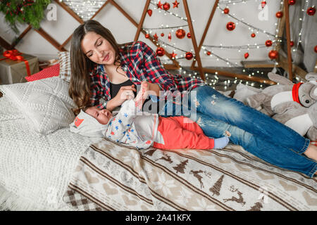 Mutter und Kind liegen auf einer neuen Jahre Bett. Mummys kleiner Junge. Mutter und ihrem Baby zu Hause. Stockfoto