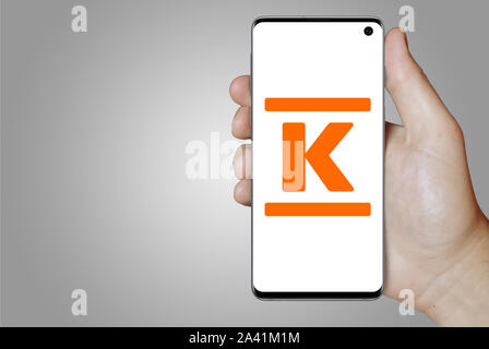 Ein Mann hält ein Telefon mit dem Logo der Firma Kesko im OMX Helsinki notiert. Grauen Farbverlauf Hintergrund. Credit: PIXDUCE Stockfoto