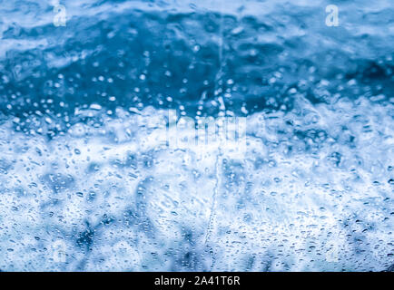 Wassertropfen fallen in den Glashintergrund. Stockfoto