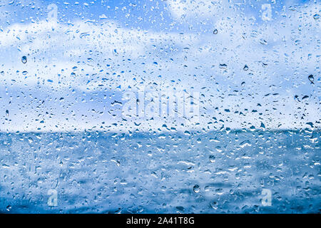Wassertropfen fallen in den Glashintergrund. Stockfoto