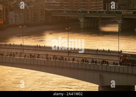 Ende des Arbeitstages und Pendler zu Fuß über die London Bridge, wie die Sonne Stockfoto