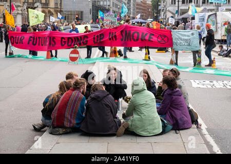 Jungen Demonstranten sitzen Diskussionen in einer Gruppe zu einem Aussterben Rebellion Straße Block an der Victoria Street, Westminster, London