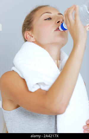 Schöne junge Frau, die nach dem Training mit einem Tuch und kaltem Wasser abkühlen. Stockfoto