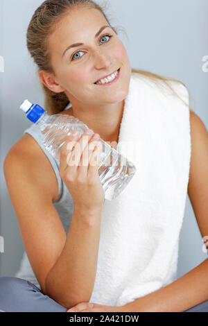 Schöne junge Frau, die nach dem Training mit einem Tuch und kaltem Wasser abkühlen. Stockfoto