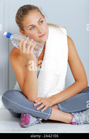 Schöne junge Frau, die nach dem Training mit einem Tuch und kaltem Wasser abkühlen. Stockfoto