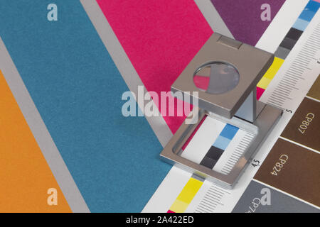 Silber Lupe stehend auf dem Testdruck, farbigen Hintergrund. Drucken Lupe auf Offset gedrucktes Blatt mit grundlegenden Farben- und Symbolleisten. Stockfoto