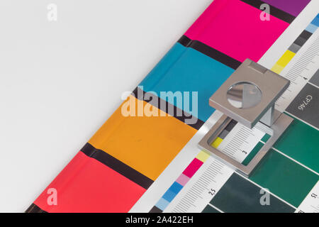 Silber Lupe stehend auf dem Testdruck, farbigen Hintergrund. Drucken Lupe auf Offset gedrucktes Blatt mit grundlegenden Farben- und Symbolleisten. Stockfoto