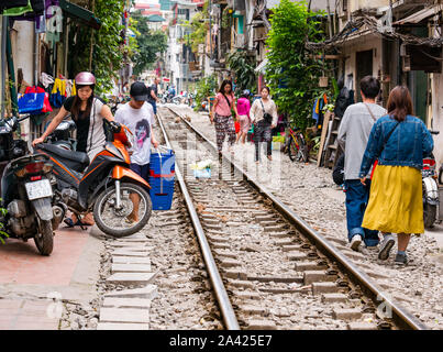 Die Menschen vor Ort und die Roller in Railway Village schmale Gasse mit Bahnlinie, Hanoi, Vietnam, Asien Stockfoto