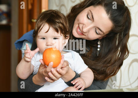 Mom bietet eine Orange zu einem Kind. Vitamine auf das Kind. Obst gesunde Ernährung für Kinder. Stockfoto